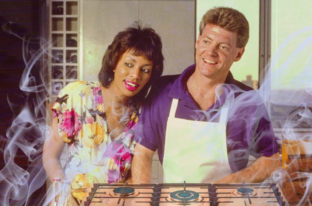 A couple standing in front of a gas stove, with smoke wisps all around them